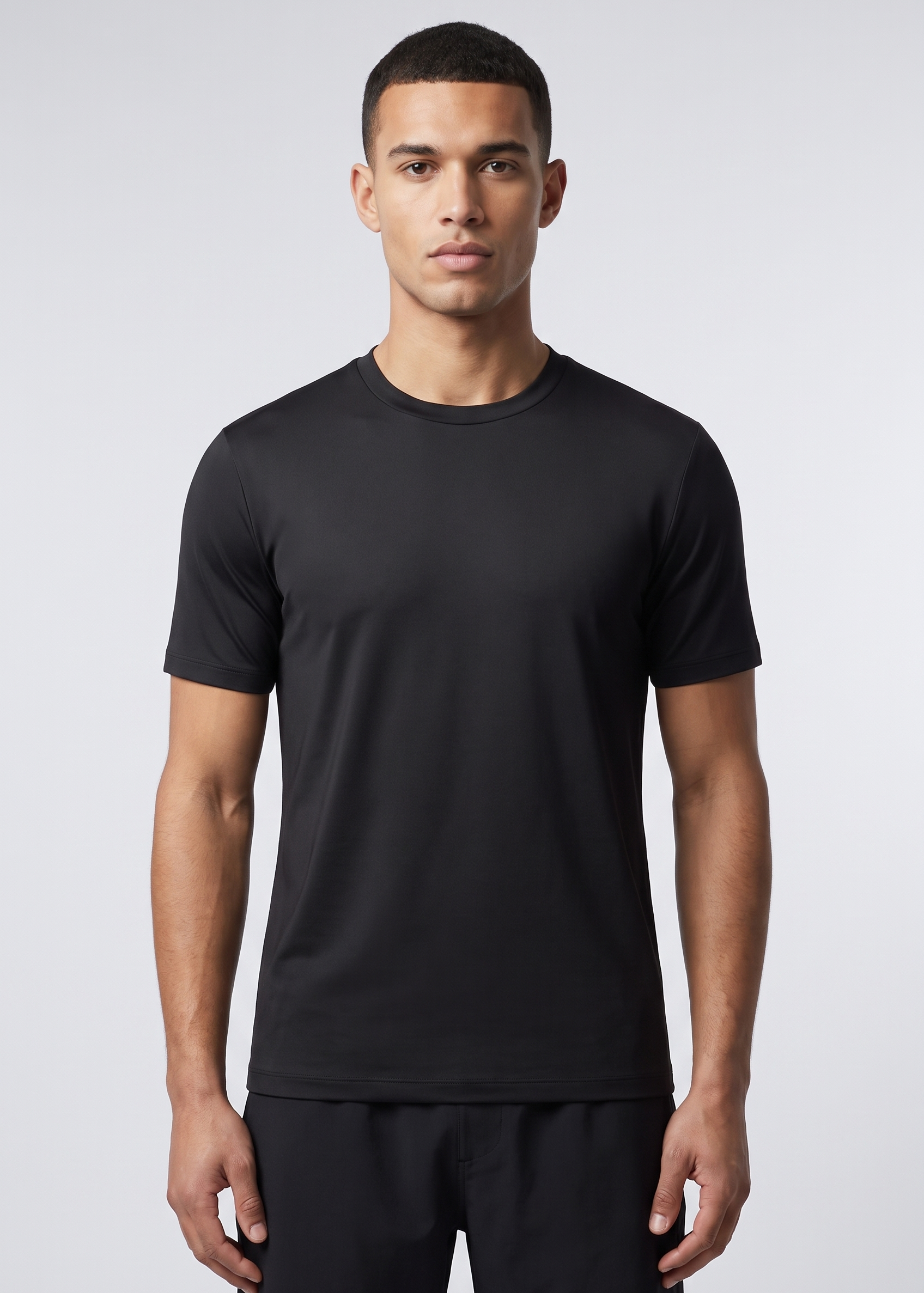 Homme portant le T-Shirt Shiny noir MONVALERE, vue de face, cadrage mi-cuisse, fond studio gris clair