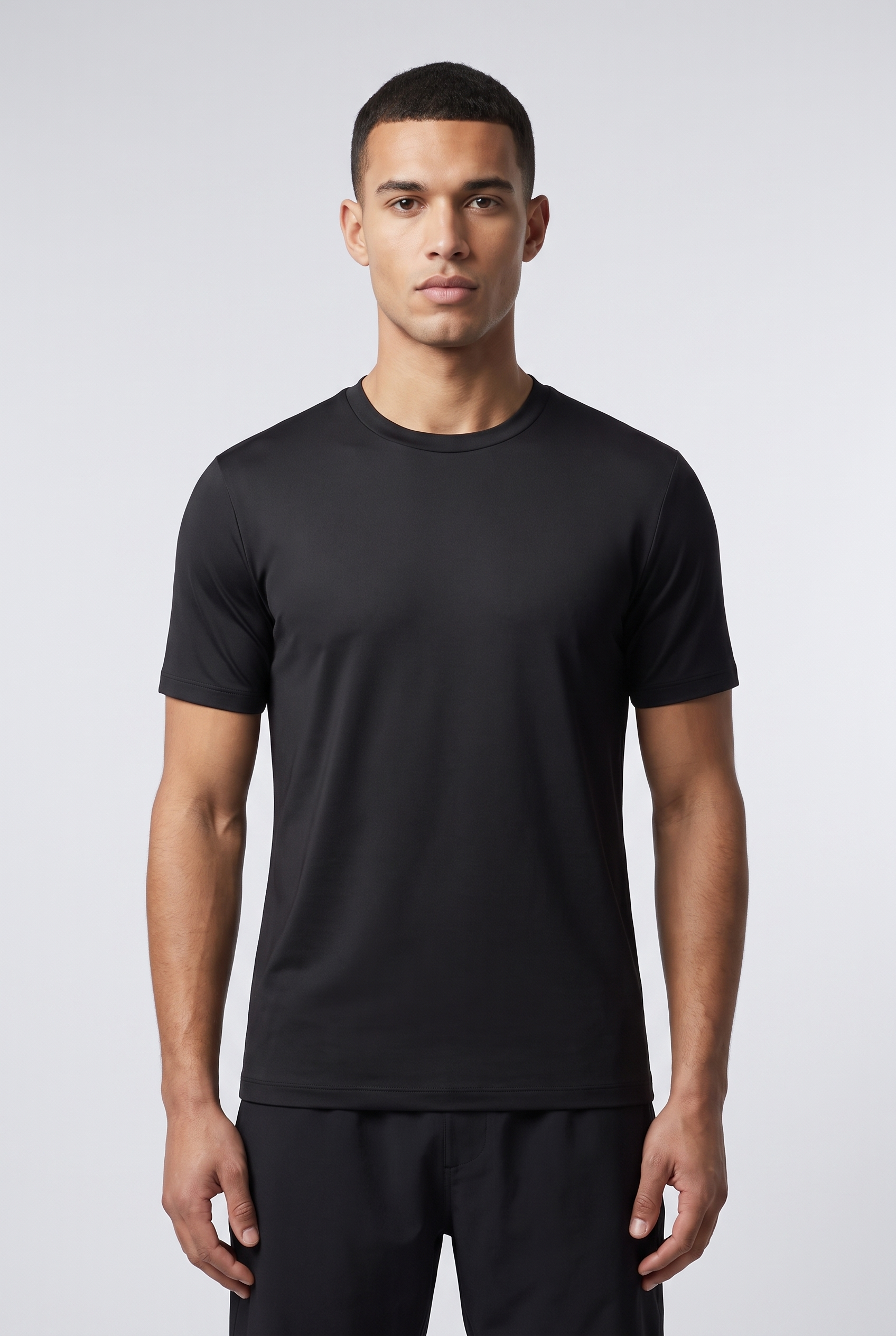 Homme portant le T-Shirt Shiny noir MONVALERE, vue de face, cadrage mi-cuisse, fond studio gris clair