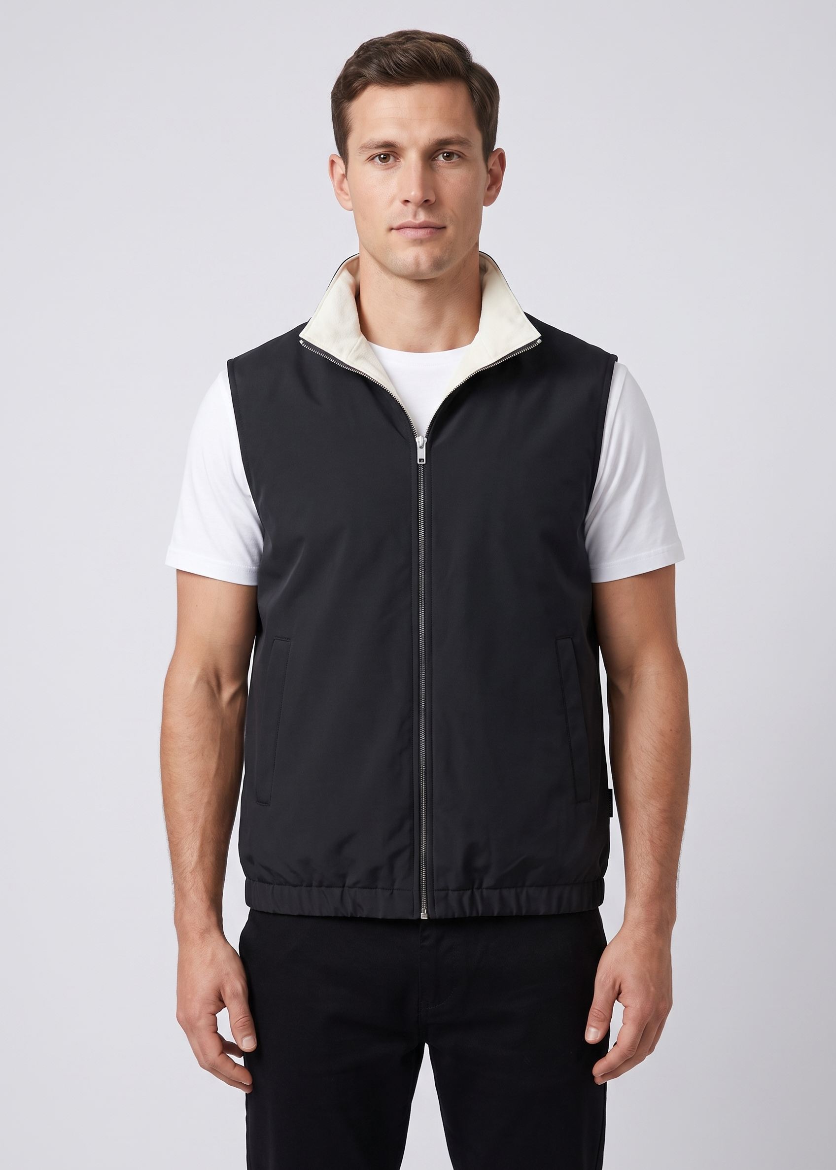 Homme portant le gilet sans manches reversible MONVALERE cote noir, vue de face, cadrage mi-cuisse, fond studio gris clair