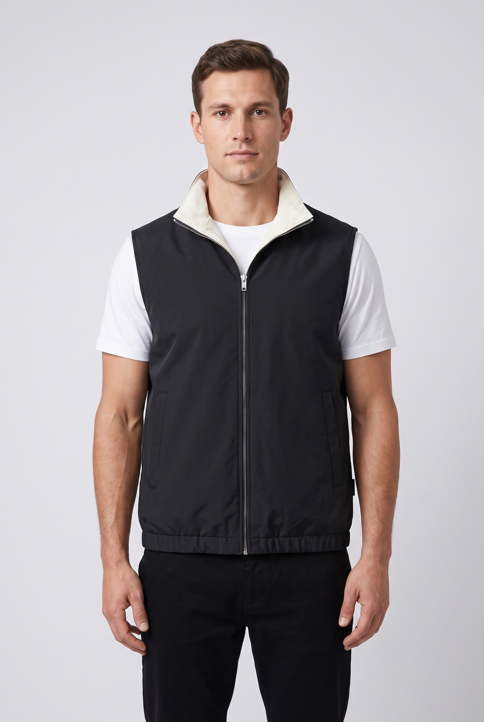 Homme portant le gilet sans manches reversible MONVALERE cote noir, vue de face, cadrage mi-cuisse, fond studio gris clair