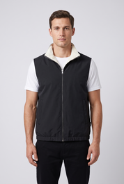 Homme portant le gilet sans manches reversible MONVALERE cote noir, vue de face, cadrage mi-cuisse, fond studio gris clair
